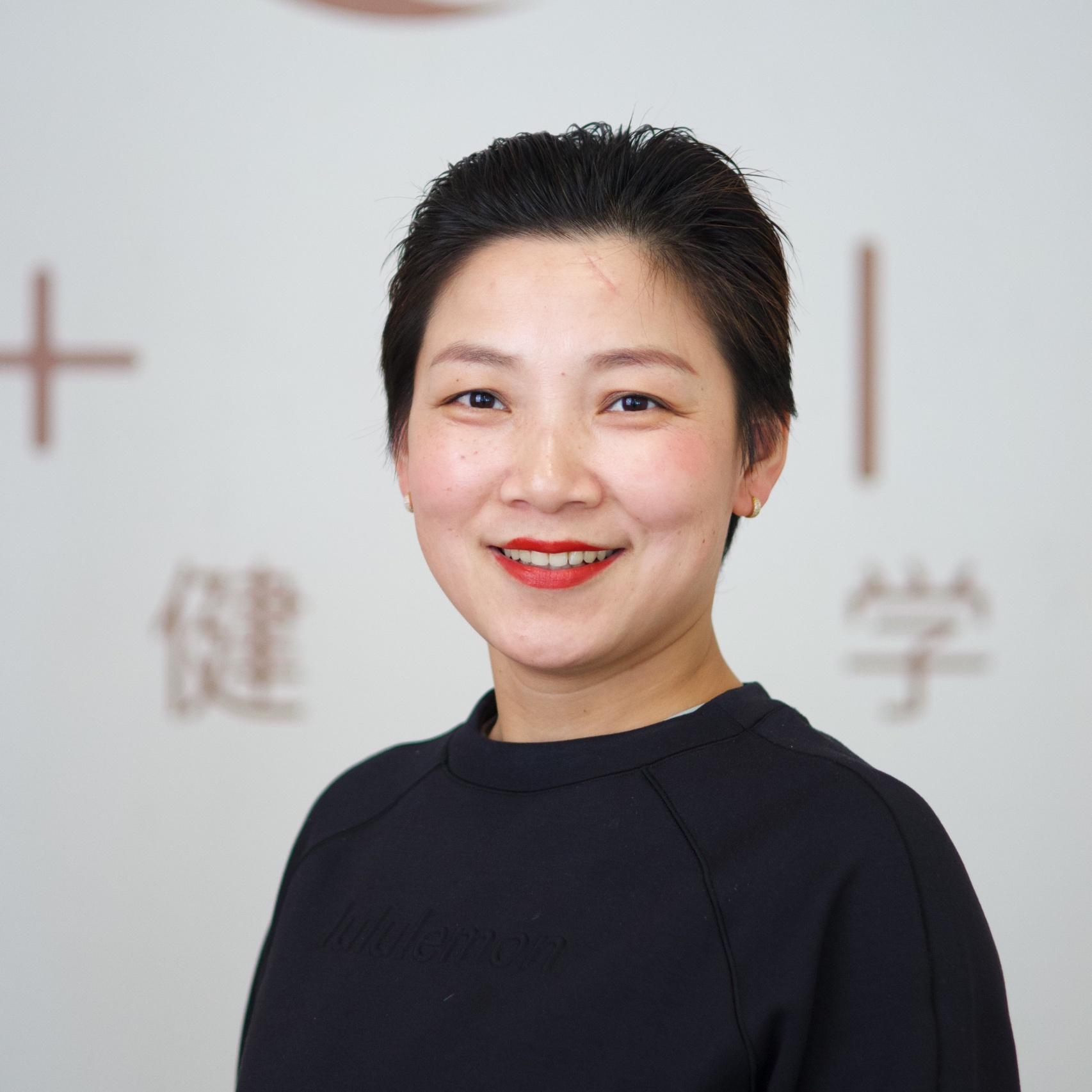当然!以下是包含您要求的关键字的图片描述示例:一位深色短发、身着黑色上衣的女士对着镜头热情微笑,暗示着阿卡迪亚或钻石吧瑜伽和普拉提工作室的温馨氛围。浅色背景上有部分可见的文字和健身符号,巧妙地暗示了各种课程,如普拉提课程、瑜伽课程、钢管课程、蹦极健身、飞行瑜伽和蹦极瑜伽。如果您需要为特定使用情况(如社交媒体alt-text或网站描述)量身定制,请告诉我